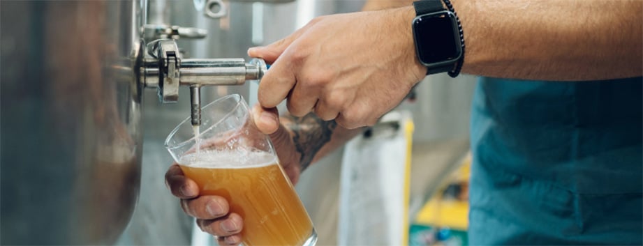 Un barman verse de la bière d'un robinet dans un verre à pinte