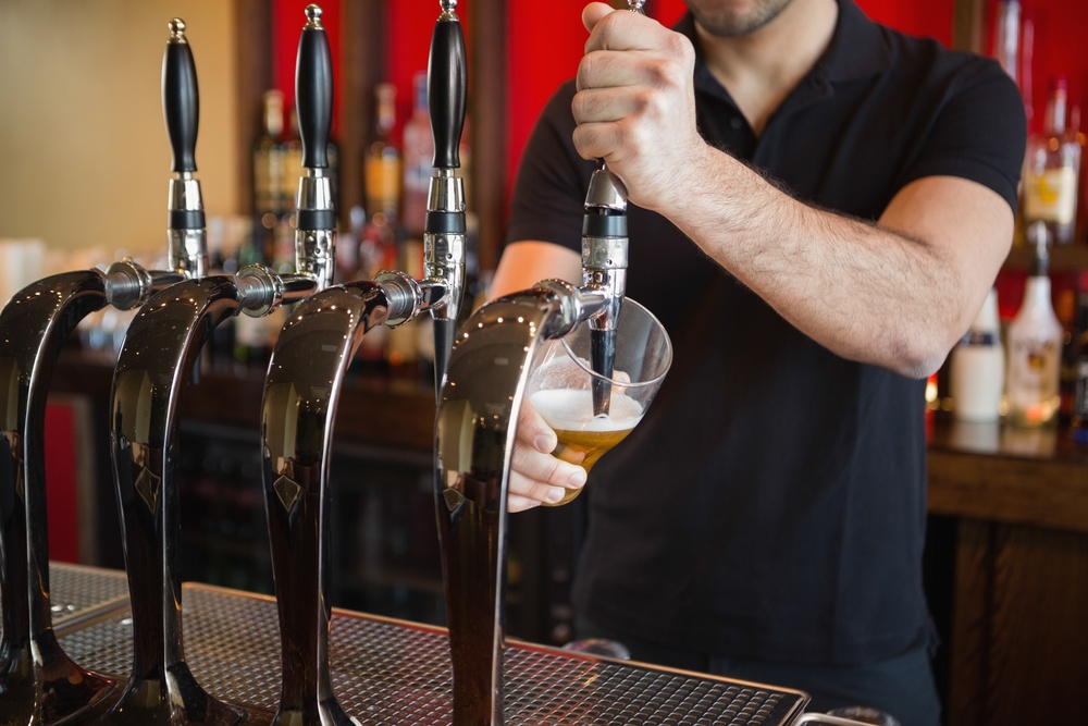 Barman tirant une pinte de bière derrière le bar