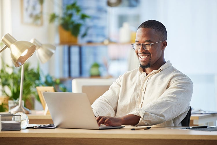 Businessman wearing glasses smiles as he works on his laptop